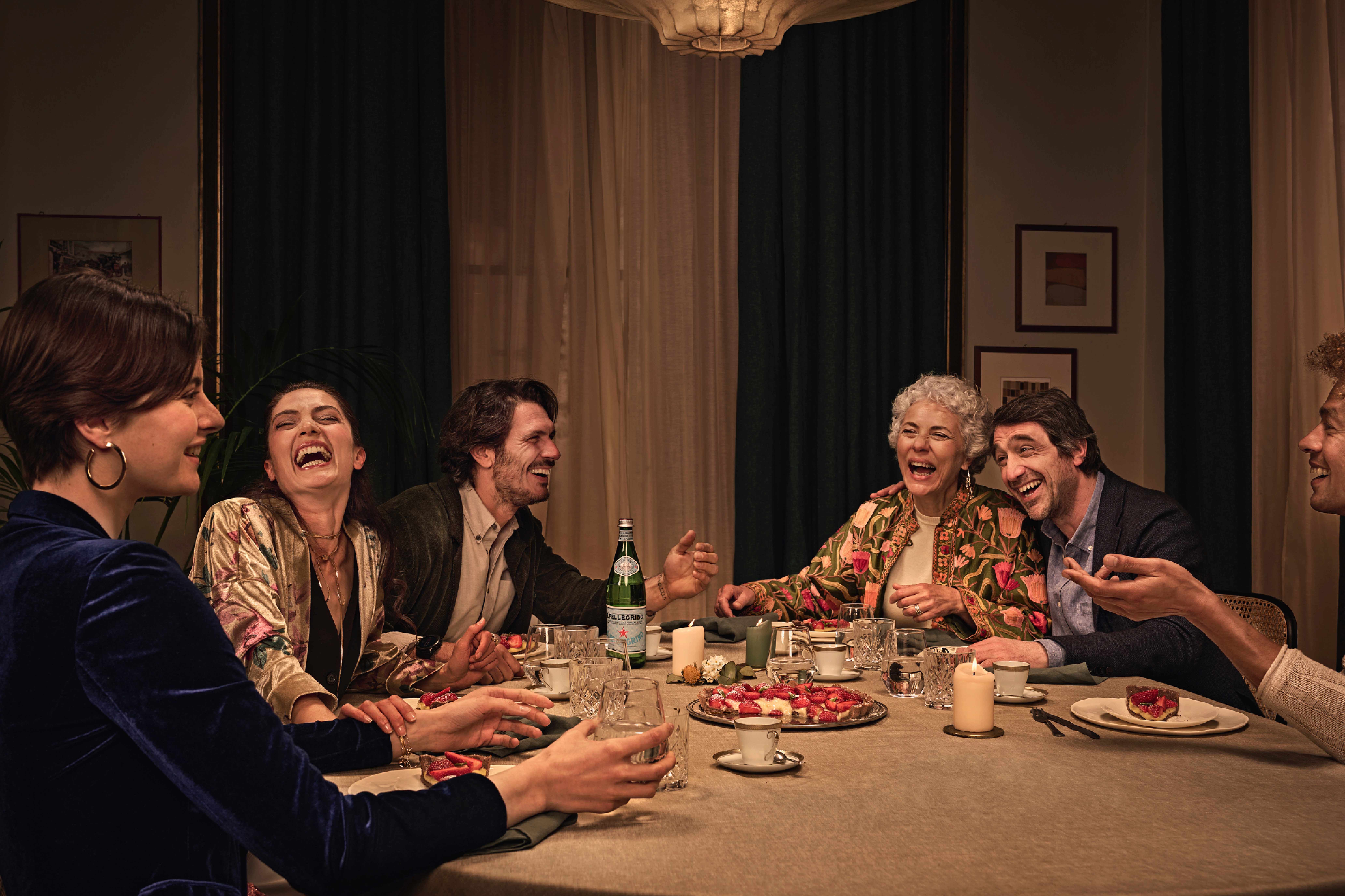 Des amis dînent ensemble à la maison en partageant une bouteille de S.Pellegrino.