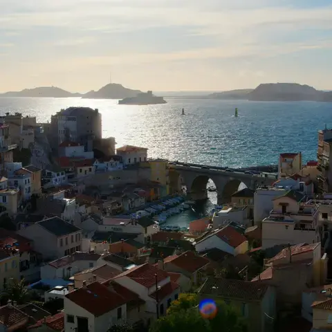 Vue sur le Vallon des Auffes à Marseille, port pittoresque aux maisons colorées, avec les îles du Frioul en arrière-plan.