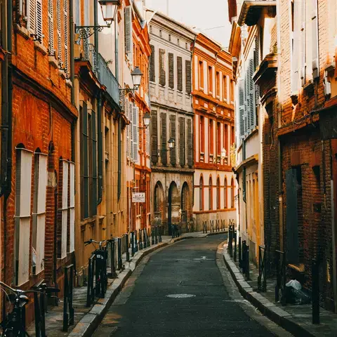 Ruelle pittoresque aux façades en briques rouges, baignée de lumière dorée, capturant l’âme authentique d’une ville du Sud.