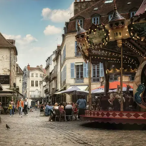 Place animée avec un carrousel rétro, terrasses de cafés et façades anciennes, capturant le charme d’une ville française.
