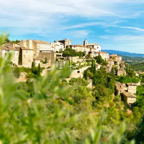 Village perché en Provence, entouré de verdure et baigné de soleil, offrant une vue panoramique sur la vallée et les montagne