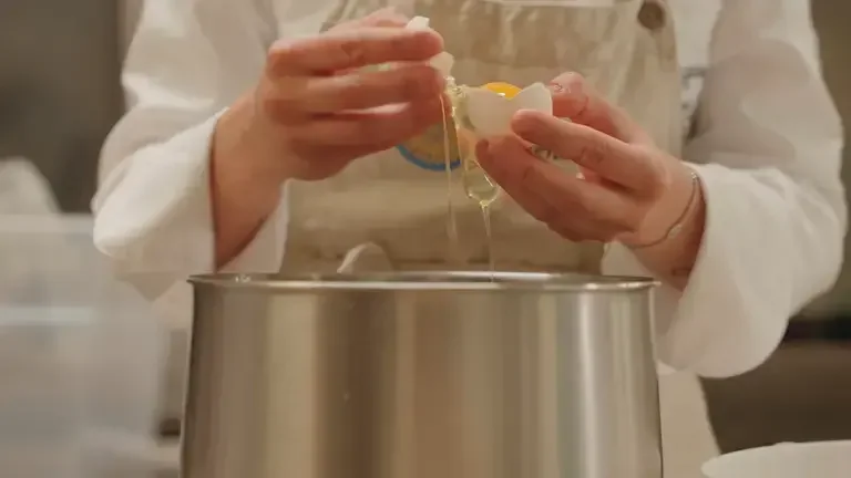 La cheffe casse les œufs pour la meringue