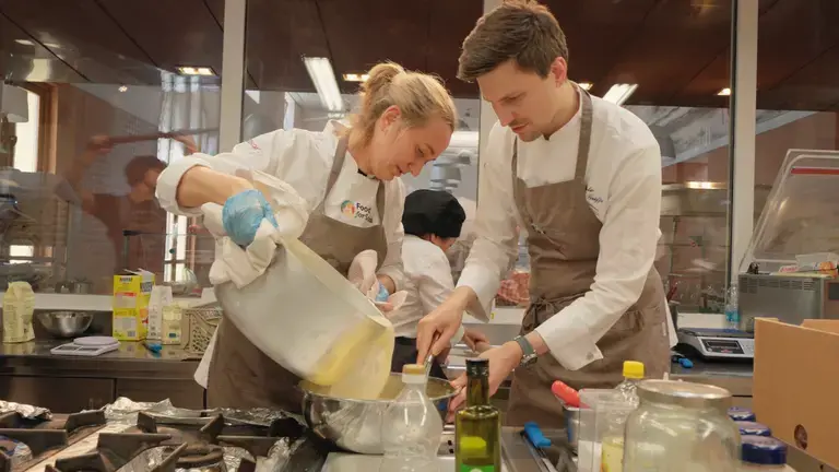 Chefs collaborant dans une cuisine professionnelle, versant de la pâte dans un bol