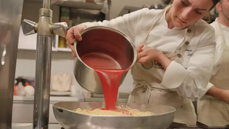 Chef assaisonnant des spaghetti à la tomate