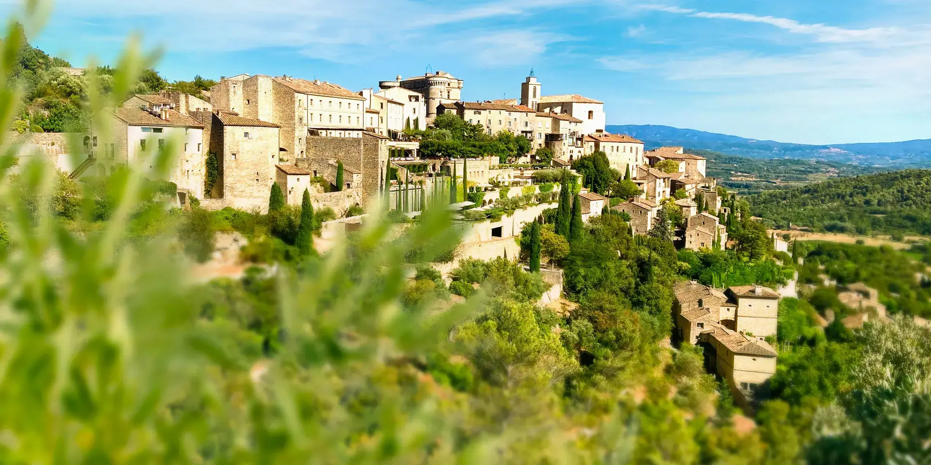 Village perché en Provence, entouré de verdure et baigné de soleil, offrant une vue panoramique sur la vallée et les montagne