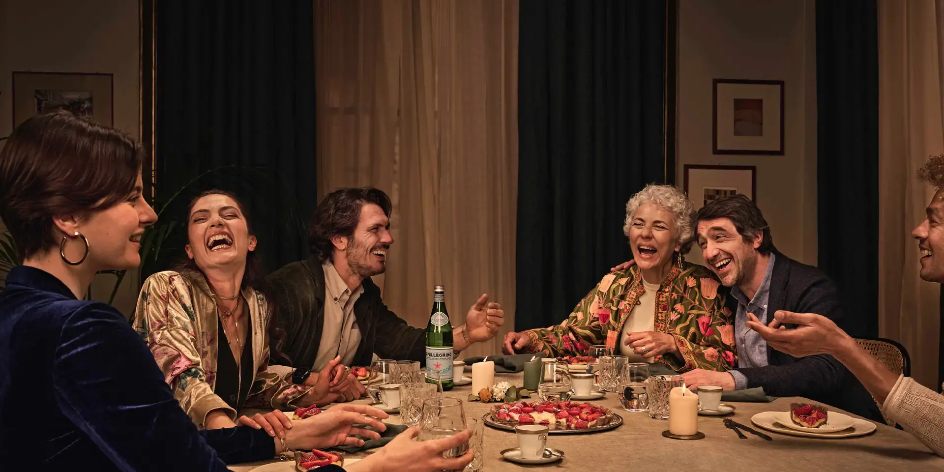 Des amis dînent ensemble à la maison en partageant une bouteille de S.Pellegrino.