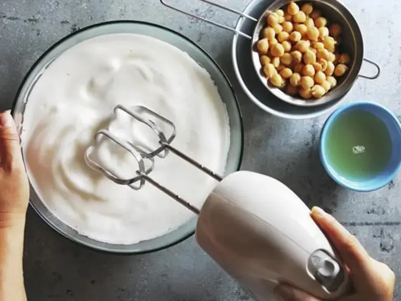 pois chiches dans une petite passoire et aquafaba montée en neige avec un batteur